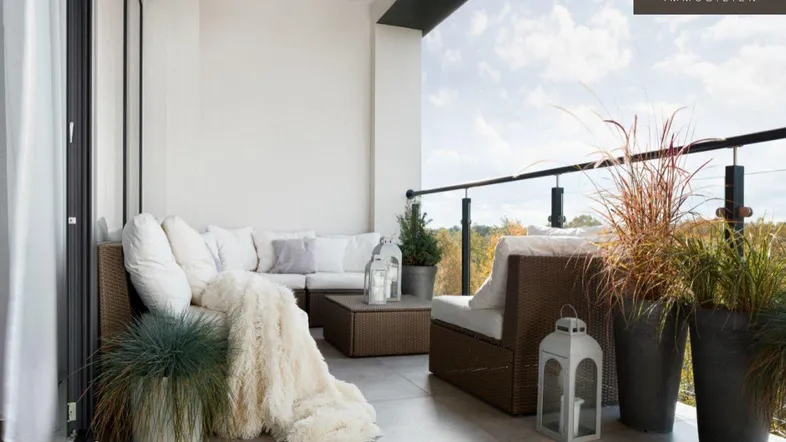 Gemütlicher Balkon mit modernen Outdoor-Möbeln und Blick ins Grüne sowie auf die Stadt.