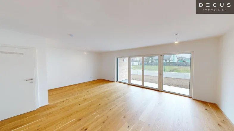 Helles Wohnzimmer mit Holzboden und großen Schiebetüren zum Gartenbereich.