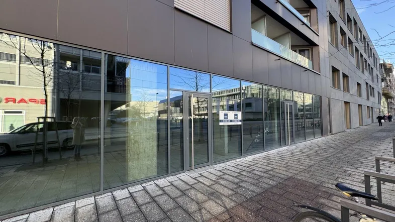 Moderne Geschäftsfassade mit großen Glasfenstern und Bürgersteig, ideal für Ladenlokale.