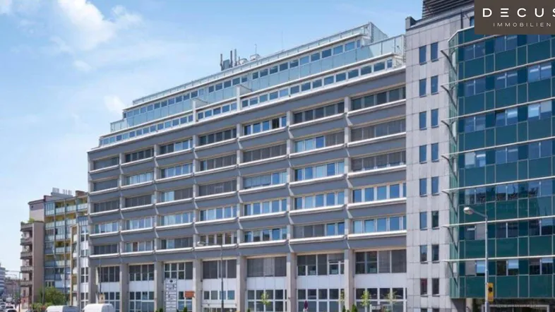 Modernes Bürogebäude mit gestufter Fassade und großen Fensterfronten unter blauem Himmel.
