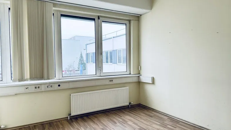 Heller Büroraum mit Laminatboden, großen Fenstern und Heizkörpern, ideal für Arbeitsplätze.