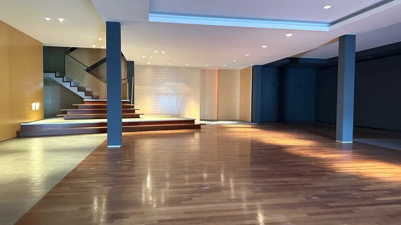 Geräumiger offener Bereich mit Holzboden, erhöhter Plattform und einer modernen Treppe im Hintergrund.