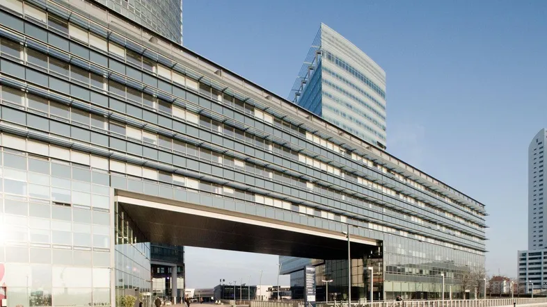 Moderne Architektur mit einer beeindruckenden Glasfassade und einer markanten Brückenkonstruktion, die das Gebäude verbindet.
