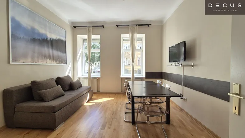 Gemütlicher Wohn-Essbereich mit Sofa, Esstisch, Holzboden und viel natürlichem Licht.