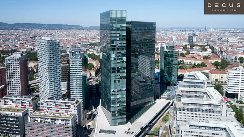 Luftaufnahme einer modernen Skyline mit hohen Glasfassaden und weitem Stadtblick über Wien.