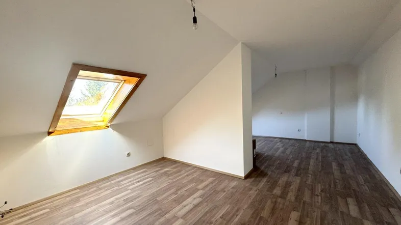 Helles Dachgeschosszimmer mit Laminatboden und Dachfenster, bereit für die individuelle Gestaltung.