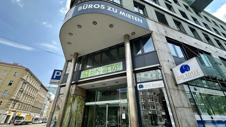 Eingangsbereich eines modernen Geschäftsgebäudes mit Büros und Läden zur Miete an einer belebten Straße.