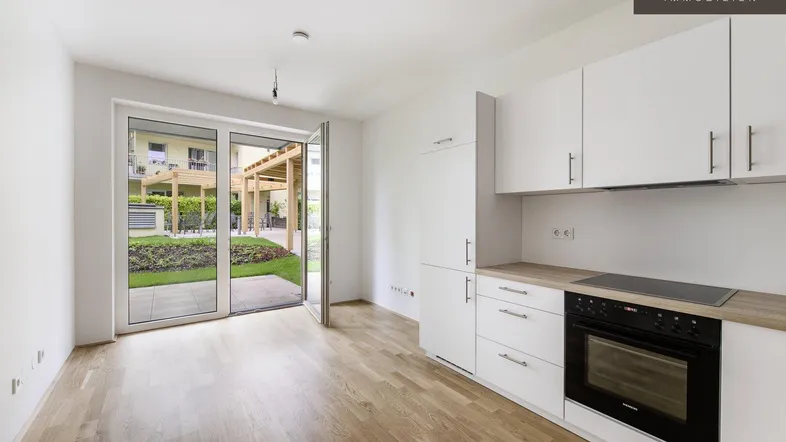 Helle, offene Küche mit modernen weißen Schränken, Holzboden und direktem Zugang zum Garten.