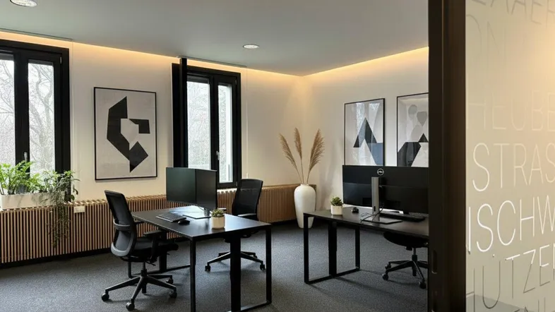 Modernes Büro mit zwei Arbeitsplätzen, großen Fenstern und stilvoller Dekoration.