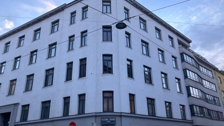 Klassisches Eckgebäude in städtischer Umgebung mit mehreren Etagen und traditioneller Architektur.