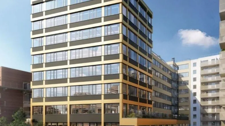 Modernes Bürogebäude mit markanter Fassade und großen Fenstern, umgeben von Grünflächen und Fußgängern.
