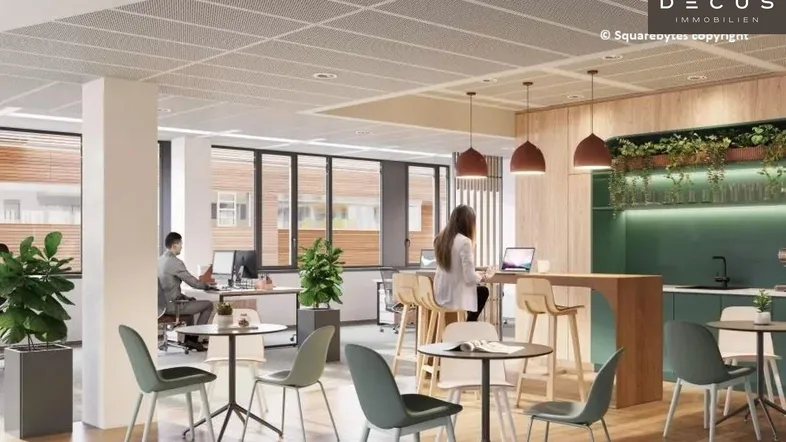 Moderner Bürobereich mit Gemeinschaftsküche, Arbeitsplätzen und großen Fenstern für viel Tageslicht.
