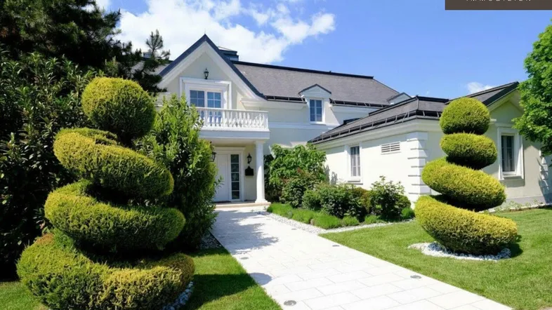 Elegante Villa mit gepflegtem Vorgarten, weißem Kiesweg und kunstvoll geschnittenen Büschen.