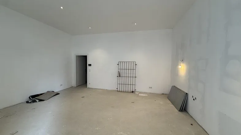 Geräumiger, unmöblierter Gewerberaum mit weißen Wänden und Betonboden, bereit für den Innenausbau.
