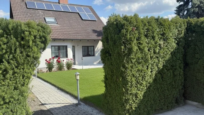 Gepflegter Vorgarten mit Rasenfläche, Hecken und Rosen vor dem Einfamilienhaus mit Solaranlage.