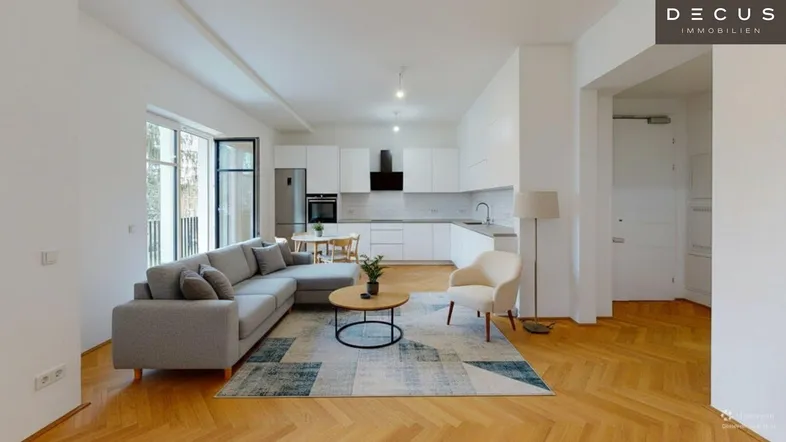 Heller, offener Wohn-Essbereich mit integrierter Küche, Parkettboden und Zugang zum Balkon.