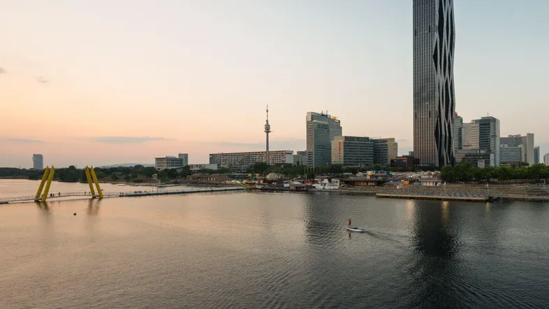 Panoramablick auf die Donau und die Skyline von Wien mit dem modernen DC Tower bei Sonnenuntergang.
