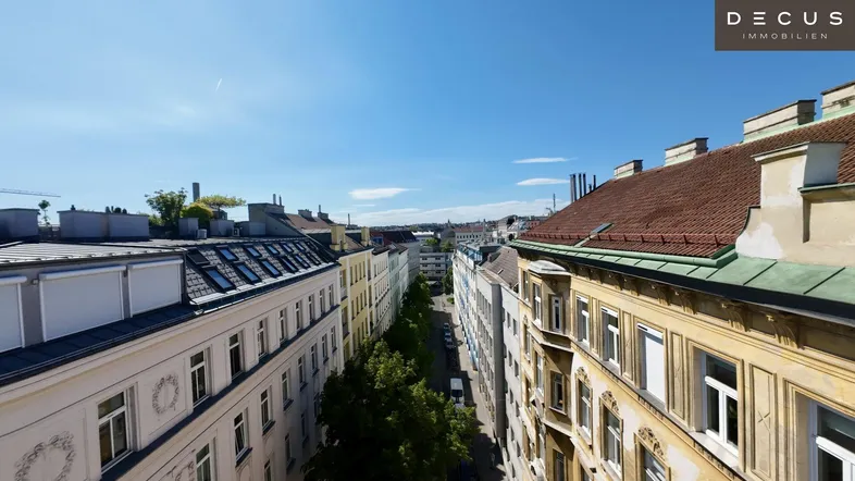Weitläufiger Blick über eine belebte Stadtstraße mit historischen Gebäuden und blauem Himmel.