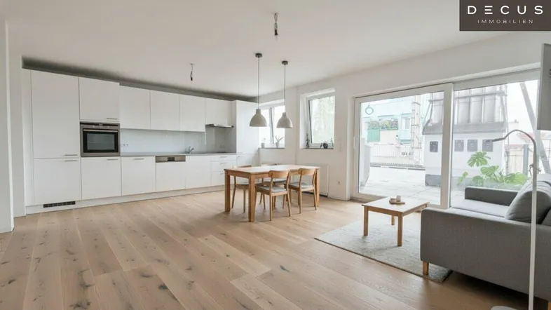 Heller, offener Wohn-Essbereich mit moderner Einbauküche, Holzboden und Zugang zur Terrasse.