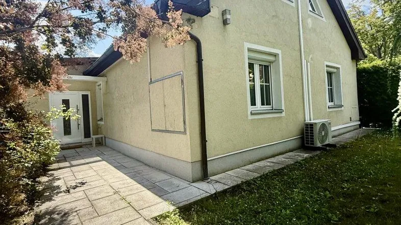 Vorderansicht des Hauses mit gepflegtem Vorgarten und Steinweg unter blauem Himmel.