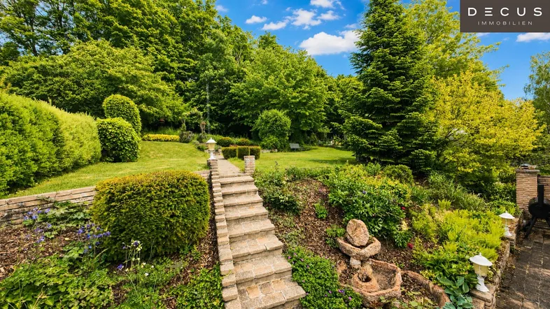 Terrassierter Garten mit Steinweg, Treppen und üppiger Bepflanzung.