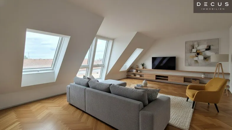 Helles, modernes Wohnzimmer mit Dachschrägen, Fischgrätparkett und großen Dachfenstern, die viel Licht hereinlassen.