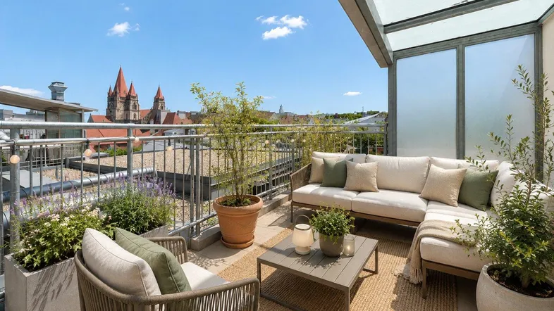 Möblierte Dachterrasse mit gemütlicher Sitzecke und weitem Blick über die Stadt und Kirche.