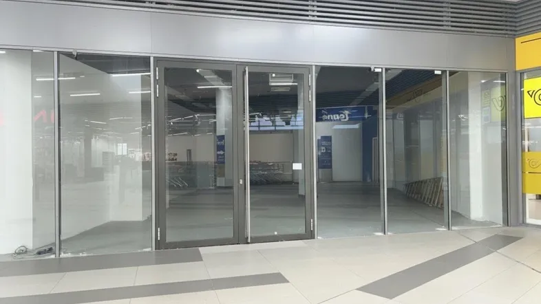 Leerer Gewerberaum mit großen Glasfronten und Fliesenboden, bereit für neue Mieter.