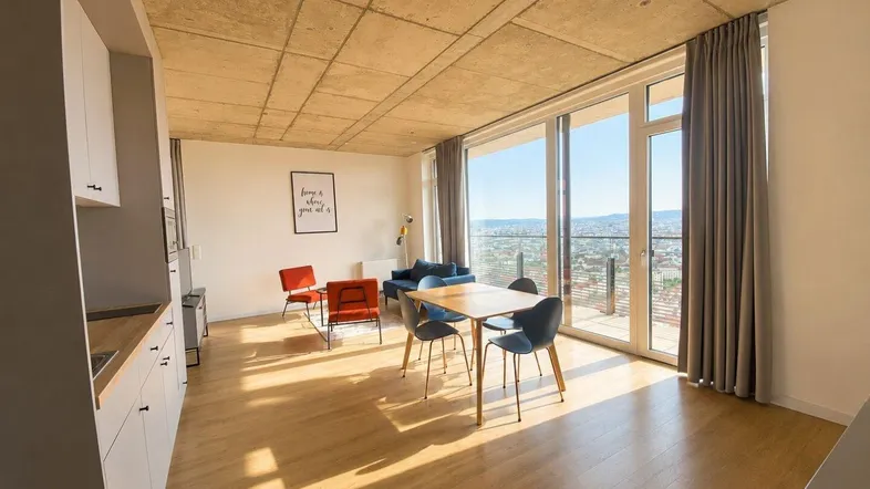 Heller Wohn- und Essbereich mit offener Küchenzeile, Holzboden und Panoramablick auf die Stadt.