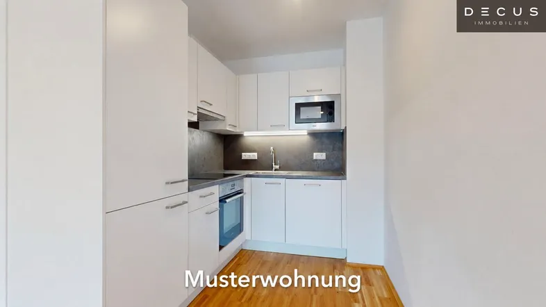 Moderne Küche mit weißen Schränken, integrierten Geräten und Holzboden in einer Musterwohnung.