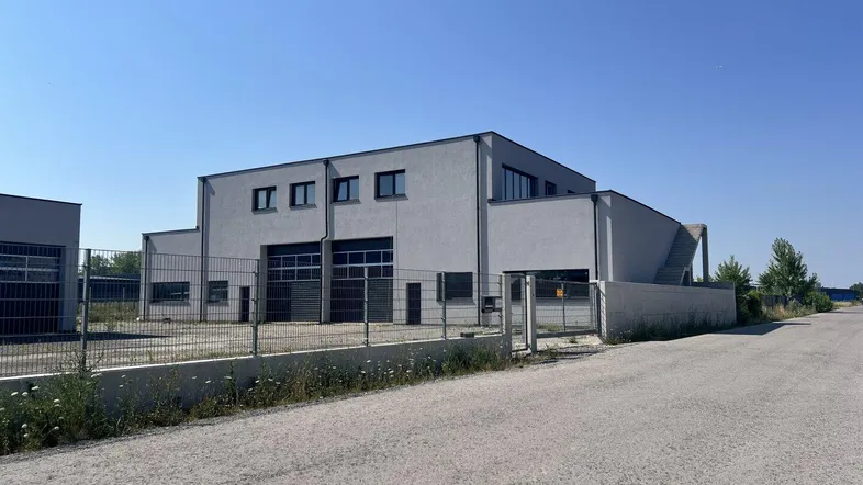 Modernes Gewerbegebäude mit grauer Fassade und großen Rolltoren unter klarem Himmel.