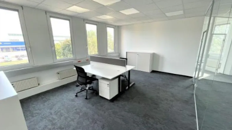 Helles Büro mit Teppichboden, großen Fenstern und moderner Einrichtung, ideal für produktives Arbeiten.