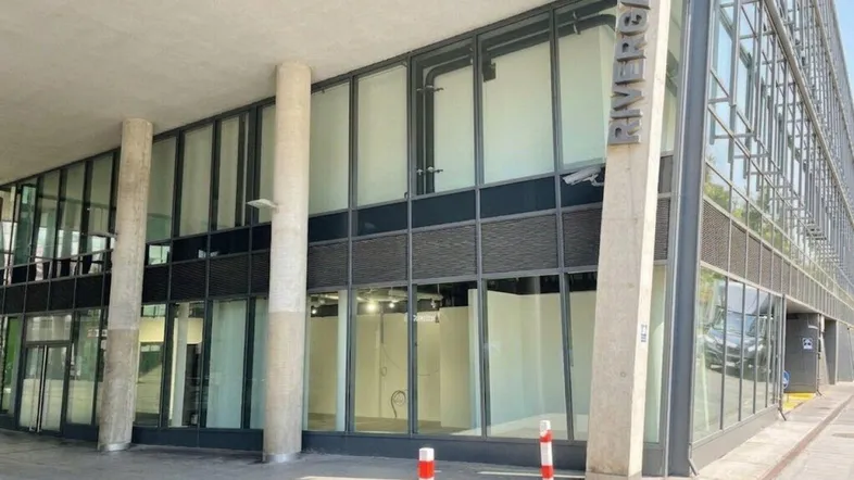 Moderne Geschäftsfassade mit großen Glasflächen und Betonpfeilern, die viel Tageslicht hereinlassen.