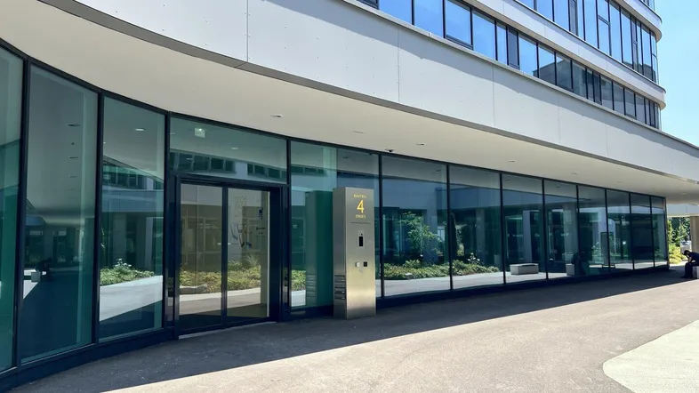 Moderner Eingangsbereich eines Bürogebäudes mit großer Glasfassade und barrierefreiem Zugang.