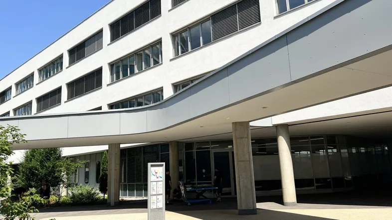 Modernes Bürogebäude mit überdachtem Eingangsbereich, großen Fenstern und gepflegter Außenanlage.