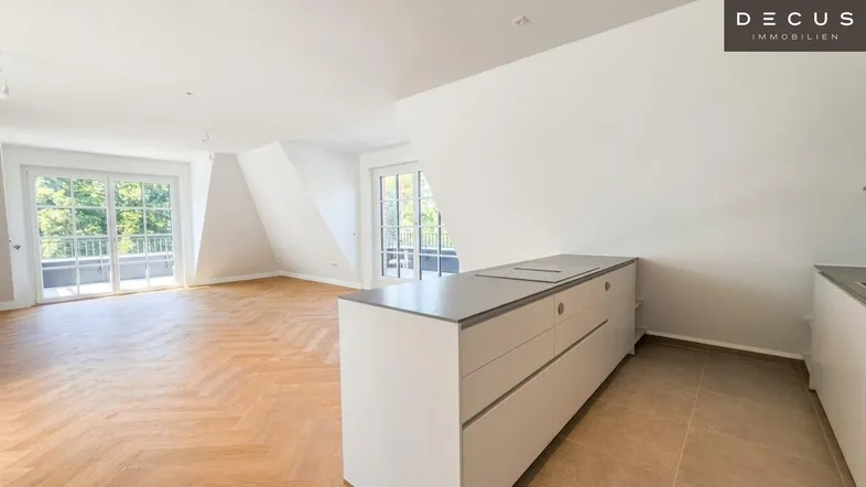 Heller, offener Wohnbereich mit Fischgrätparkett, Dachschrägen und Zugang zu mehreren Balkonen.