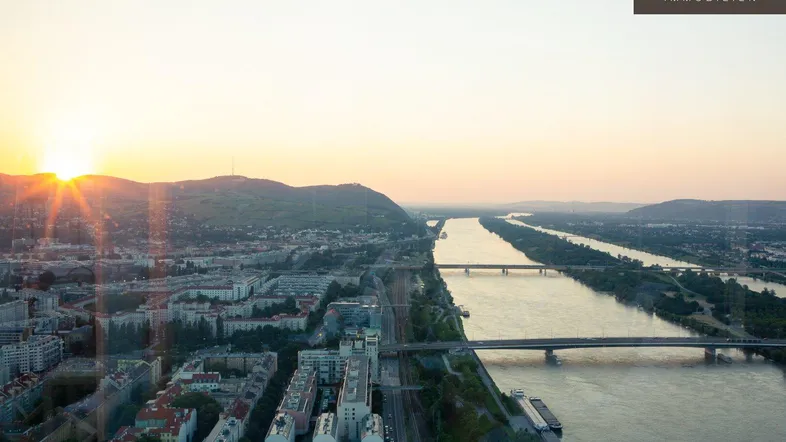 Panoramablick bei Sonnenuntergang über die Stadt, den Fluss und die umliegenden Berge.