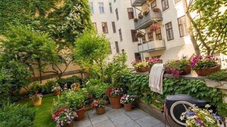 Künstlich gestaltete Terrasse mit Gartenmöbeln und üppiger Bepflanzung im Innenhof.