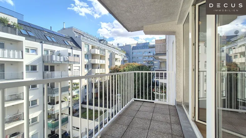 Heller Balkon mit Fliesenboden und Blick auf die umliegenden Wohngebäude.