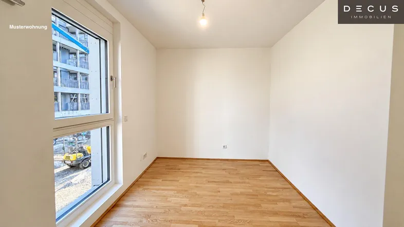 Helles Zimmer mit Holzboden und großem Fenster, das einen Blick auf die Baustelle bietet.