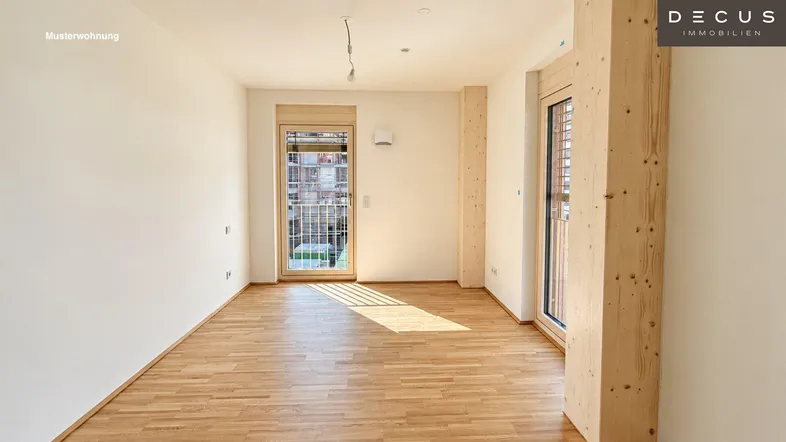 Heller, leerer Wohnraum mit Holzboden, weißen Wänden und Zugang zu einem französischen Balkon.