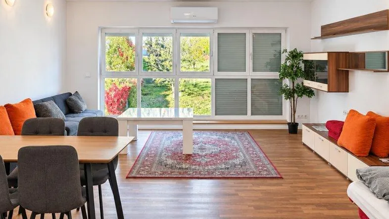 Helles Wohnzimmer mit Holzboden, großen Fenstern und Zugang zum Gartenbereich.