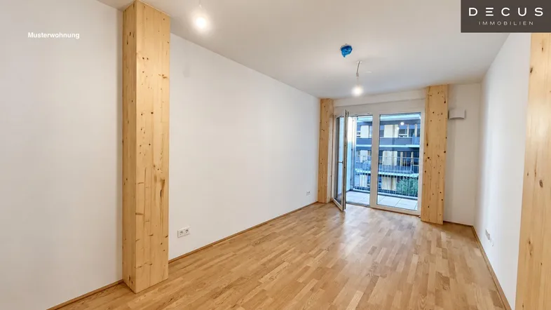 Helles Zimmer mit Holzboden und Zugang zu einem Balkon, ideal als Wohn- oder Schlafzimmer.