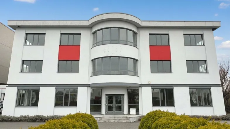 Modernes Geschäftsgebäude mit weißer Fassade, großen Fenstern und markanten roten Akzenten.