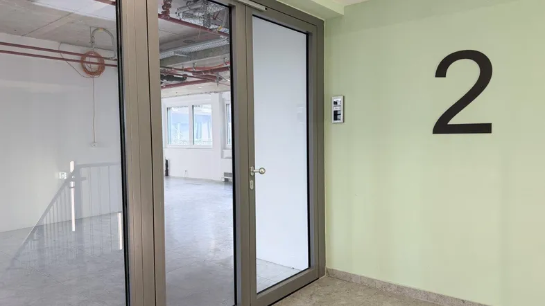 Eingangsbereich zu einem modernen Büro mit Glastüren und der Nummer 2 an der Wand.