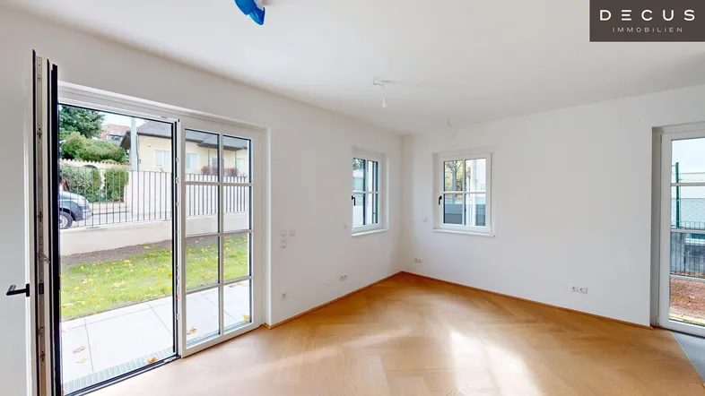 Helles Wohnzimmer mit Parkettboden, großen Fenstern und direktem Zugang zum Garten.