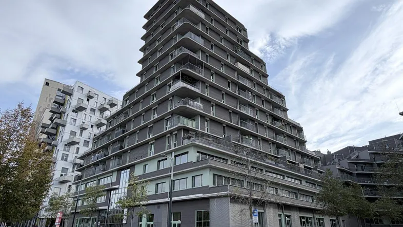Modernes Hochhaus mit gestufter Architektur und zahlreichen Balkonen in städtischer Umgebung.