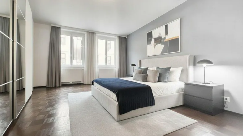 Helles Schlafzimmer mit modernem Design, Parkettboden und großem Spiegelkleiderschrank.