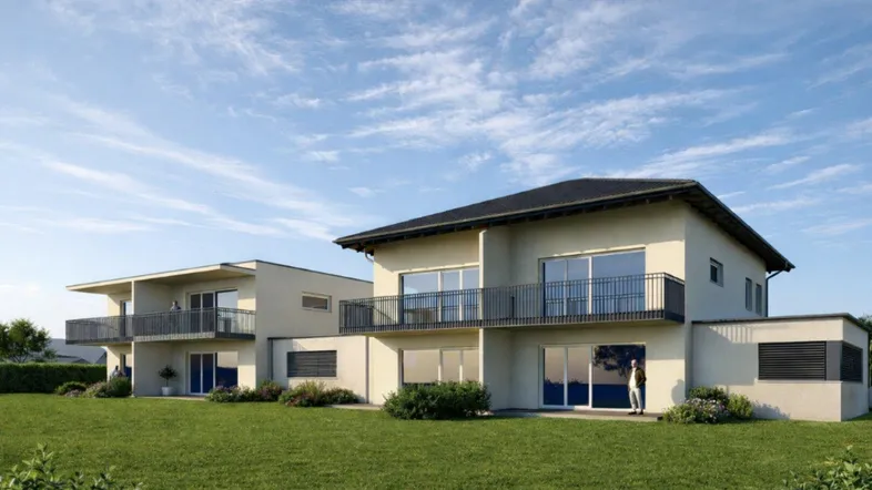 Moderne Doppelhäuser mit gepflegtem Rasen und Balkonen unter blauem Himmel.
