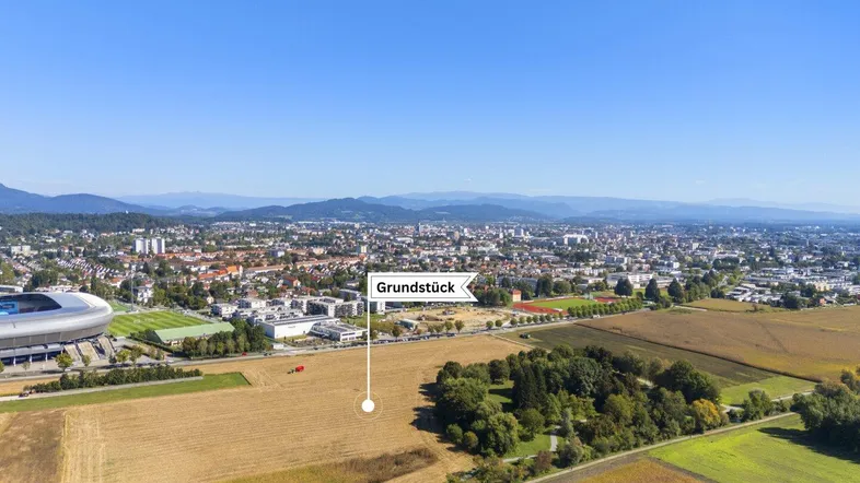 Luftaufnahme eines Grundstücks mit Blick auf die Stadt und umliegende Felder unter blauem Himmel.